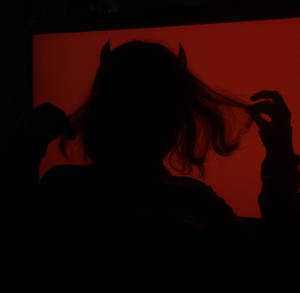 一個帶有惡魔角的人的剪影，在紅色光芒中。 — 惡魔角 壁紙