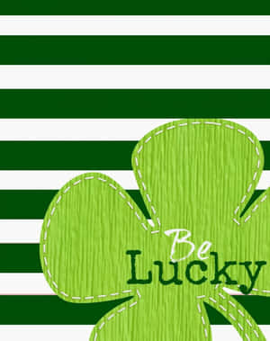 綠色和白色條紋上帶有白色縫線和「Be Lucky」文字的綠色三葉草。 — 4:5 壁紙