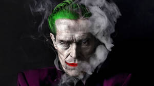 一個帶有綠色頭髮和紅色嘴唇的威脅性小丑被煙霧包圍。 — 小丑 壁紙