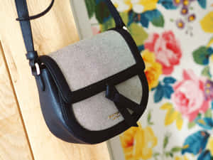 黑色皮革斜挎包帶網狀面板，背景為花卉壁紙。 — Kate spade 壁紙