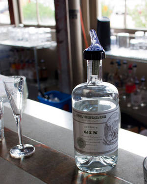 帶藍色塞子的琴酒瓶在酒吧上，旁邊有空杯。 — 品牌 壁紙