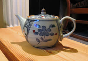 一個裝飾性的陶瓷茶壺，上面有藍色花朵，放在木桌上。 — 溫馨聖誕氛圍 壁紙