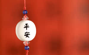 帶有和平漢字的白色陶瓷護身符掛在帶藍色珠子的紅繩上。 — 新年快樂 2020 壁紙