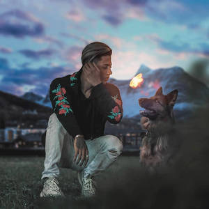 男人和德國牧羊犬在暮色中的山間草原上與蝴蝶共享寧靜時刻。 — 德國狼犬 壁紙