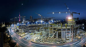 夜間城市建築工地，有起重機和發光塔樓。 — 夜空 壁紙