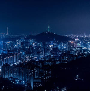 城市夜景，有發光的建築物和一座帶有發光塔樓的山。 — 夜景城市 壁紙