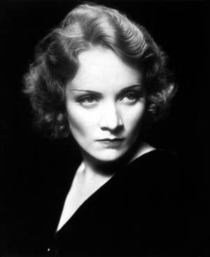一位擁有捲髮和銳利眼神的女性，在黑白工作室肖像中。 — 瑪琳·黛德麗 壁紙