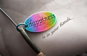 一個刻有「Happiness」的彩虹色飾物放在一隻手上，附近寫著「is in your hands...」。 — 情侶擁抱 壁紙