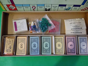 復古大富翁遊戲組件整齊地排列在原裝盒中。 — 地產大亨 壁紙