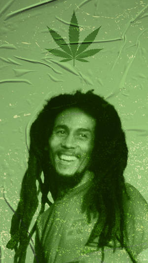 Bob Marley微笑，頭頂上方有一片大麻葉，背景為帶紋理的綠色。 — 巴布·馬利語錄 壁紙