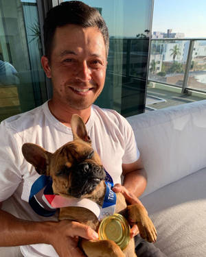 男人抱著一隻脖子上掛著奧運金牌的法國鬥牛犬。 — 可愛小狗 壁紙