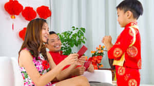 父母在室內農曆新年慶祝活動中給孩子發紅包。 — 中文 壁紙