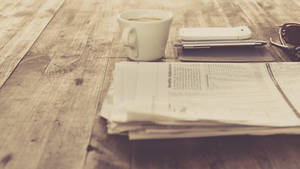 木桌上的咖啡杯、報紙、電話和太陽眼鏡。 — Old Paper 壁紙