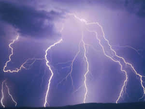 強烈的閃電劃過黑暗地平線上方暴風雨般的紫色天空。 — 閃電 壁紙