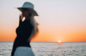 戴帽子的女人剪影，以海洋日落為背景 — 攝影 壁紙