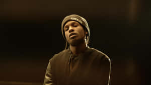 一個戴毛帽和夾克的男人在溫暖的攝影棚燈光下，有漂浮的粒子。 — ASAP Rocky 壁紙