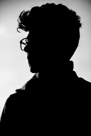 一個戴眼鏡的人的側面剪影，背景明亮。 — 男人 壁紙