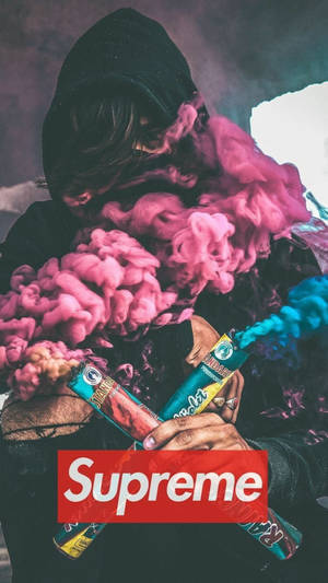 穿著黑色連帽衫的人呼出彩色煙霧，手持帶有 Supreme 標誌的煙霧彈。 — 藍色煙霧 壁紙