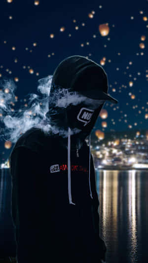 戴兜帽的人影在漂浮燈籠下呼出煙霧，背景是夜晚的城市。 — 抽菸 壁紙