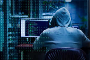 穿連帽衫的人用綠色二進位代碼覆蓋層入侵電腦 — 駭客面具 壁紙