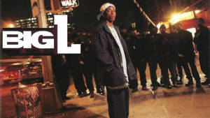 戴帽子和穿外套的男人在夜晚濕漉漉的城市街道上，帶有 'BIG L' 標誌。 — 大L 壁紙