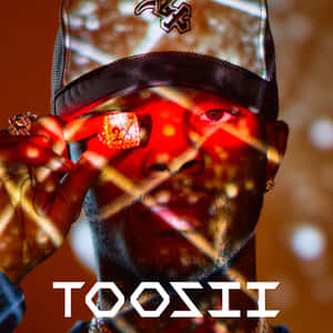 戴帽子的男人在溫暖光線下將發光紅色寶石靠近眼睛。 — Toosii 壁紙