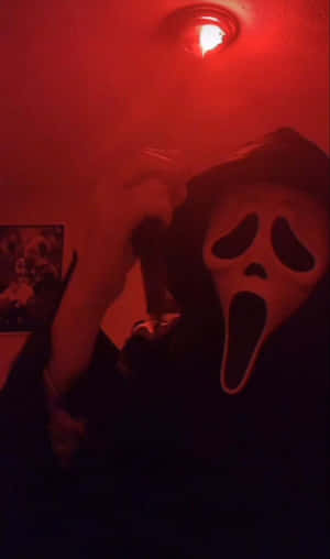 戴著Ghostface面具的人，在紅色燈光的房間裡拿著刀。 — Tecno Megapad Pro 壁紙
