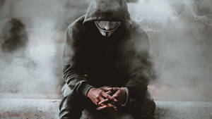 穿連帽衫和蓋伊·福克斯面具的人坐在煙霧中，雙手緊握。 — 羅賓漢 壁紙