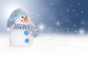 一個微笑的雪人戴著藍色帽子和圍巾站在飄雪中。 — 明亮 壁紙