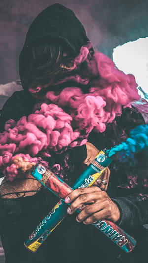 穿著黑色連帽衫的人手持煙霧彈，釋放出粉紅色和藍色煙霧。 — 藍色煙霧 壁紙