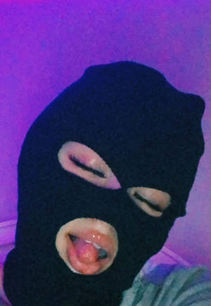 戴黑色巴拉克拉法帽的人在紫色燈光下伸出舌頭。 — 紫羅蘭 壁紙