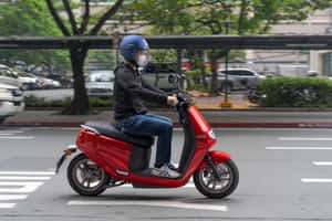 在城市街道上騎紅色滑板車的人，背景有樹木和汽車。 — 改裝摩托車 壁紙