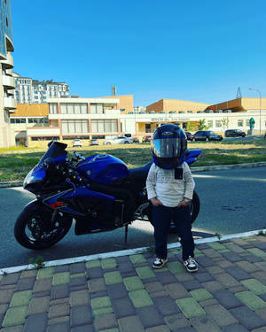 戴頭盔的孩子站在藍色摩托車旁邊的人行道上。 — 改裝摩托車 壁紙
