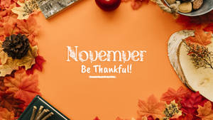 秋季扁平佈置，樹葉、松果和樺木片圍繞文字 November Be Thankful — 十一月 壁紙