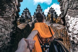 一位旅客與同伴手牽手走上寺廟小徑。 — 手牽手 壁紙