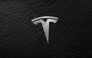 黑色皮革表面上的 Tesla 標誌 — 特斯拉 壁紙