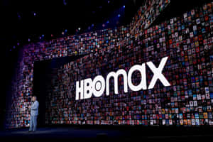 講者在HBO Max活動中進行演示，身後是一面電影海報牆。 — HBO 壁紙