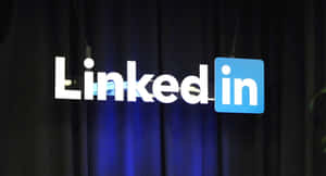 LinkedIn標誌在活動中於深藍色簾幕前亮起。 — 領英 壁紙