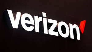 深色牆壁上帶有白色字母和紅色勾號的Verizon標誌。 — 威訊 壁紙