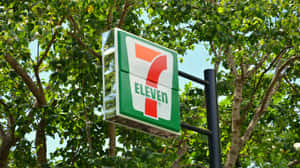 被綠樹和藍天環繞的7-Eleven商店招牌。 — 7-ELEVEN 壁紙