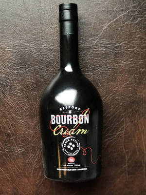 棕色皮革背景上的黑色波本奶油酒瓶 — 奶油色 壁紙