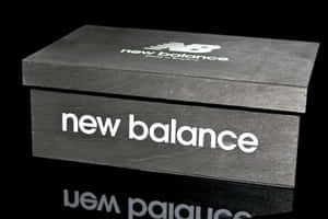 黑色New Balance鞋盒，帶有白色標誌，位於反射表面上。 — OLED 壁紙