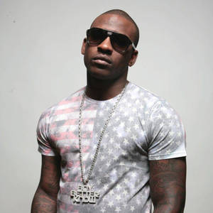 男人戴著太陽眼鏡和美國國旗T恤，戴著「Boy Better Know」鏈條。 — Skepta 壁紙