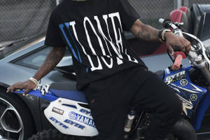 有刺青的男子騎著藍色Yamaha越野機車，旁邊有一輛灰色跑車。 — Vlone 壁紙
