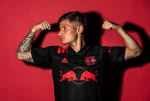 運動型男子穿著Red Bull足球球衣在紅色背景前彎曲手臂。 — 運動風 壁紙