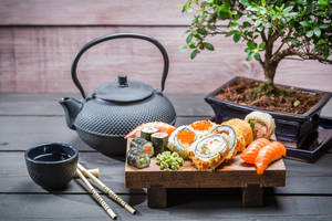 木桌上配有茶壺和盆栽的壽司拼盤 — 壽司 壁紙