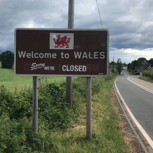 威爾斯邊境標誌，上面寫著「Welcome to WALES Sorry WE'RE CLOSED」，位於鄉村道路旁。 — 道路 壁紙