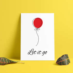 一個白色印刷品，上面有一個紅色氣球和「Let it go」短語，靠在一面有葉子的黃色牆上。 — 氣球 壁紙