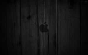 深色木牆，表面中央有一個模糊的Apple標誌。 — 4K Apple 壁紙