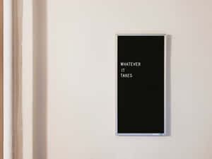 一個黑色邊框的勵志語錄標牌，上面寫著「WHATEVER IT TAKES」，位於白色牆上。 — 高清 壁紙